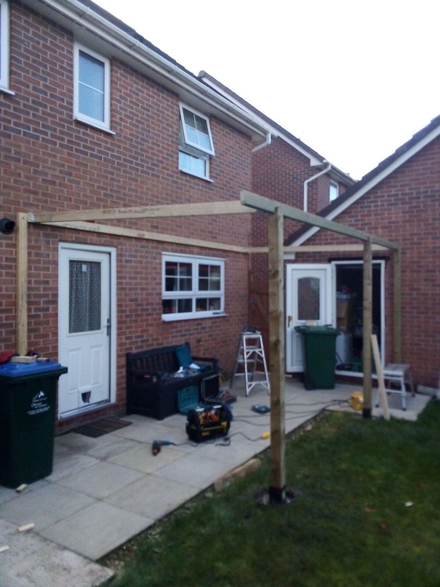 Timber frame built against the house wall over the existing patio